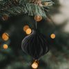 Schwarzer Weihnachtsanhänger aus Papier in Kugelform am Tannenbaum