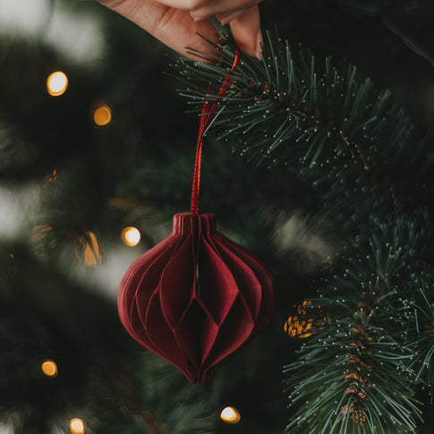Roter Papieranhänger in Kugelform am Weihnachtsbaum