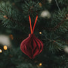 Roter Weihnachtsanhänger in Kugelform aus Papier am Tannenbaum