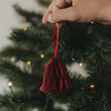 Rote Papierglocke als Christbaumschmuck wird an den Weihnachtsbaum gehängt
