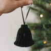 Schwarze Papierglocke als Christbaumschmuck wird an den Weihnachtsbaum gehängt