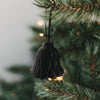 Schwarze Papierglocke aus Papier als stilvoller Christbaumschmuck am Tannenzweig