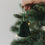 Grüne Papierglocke als Christbaumschmuck wird an den Weihnachtsbaum gehängt
