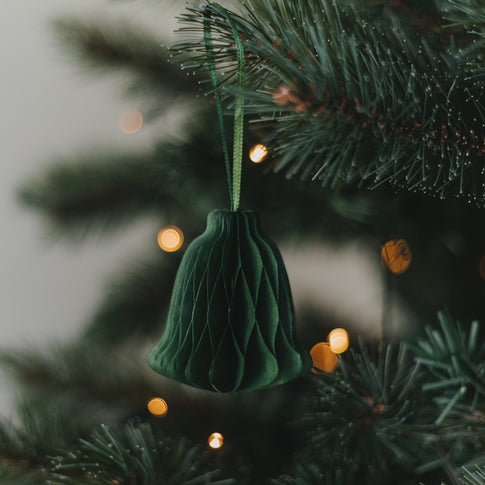 Grüne Papierglocke als Weihnachtsanhänger am festlich geschmückten Christbaum