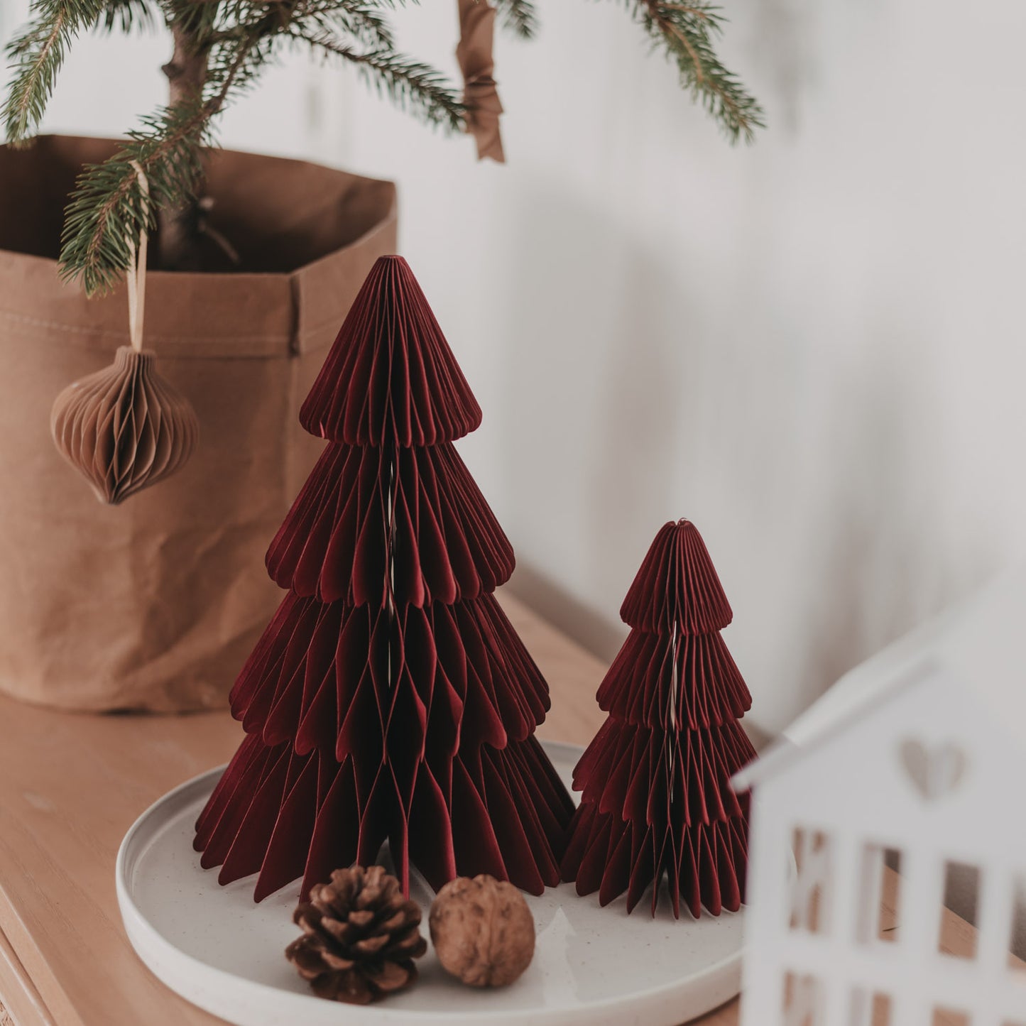 Zwei dunkelrote Papiertannen in Wabenoptik mit Tannenzapfen und  Weihnachtsdekoration