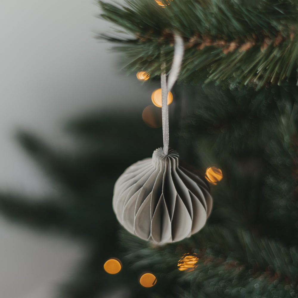 Grauer Papieranhänger in Kugelform am Weihnachtsbaum
