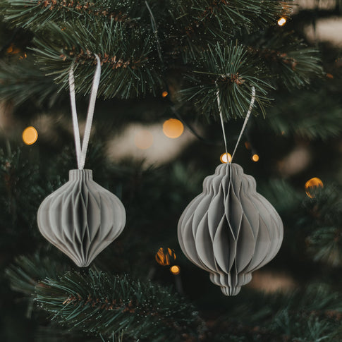 Zwei graue Papieranhänger in Kugelform als moderner Christbaumschmuck am Weihnachtsbaum