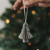 Grauer Papierbaum als Weihnachtsanhänger mit Faltoptik vor festlich geschmücktem Christbaum