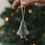 Grauer Papierbaum als Weihnachtsanhänger mit Faltoptik vor festlich geschmücktem Christbaum