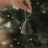 Graue Papierglocke als Christbaumschmuck wird an den Weihnachtsbaum gehängt