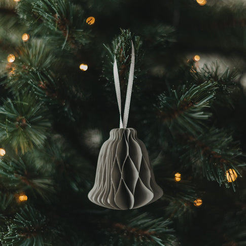 Graue Papierglocke als Weihnachtsanhänger am festlich geschmückten Christbaum