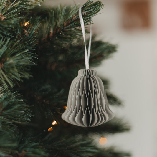 Graue Papierglocke aus Papier als Weihnachtsbaumschmuck am Tannenzweig