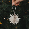 Naturfarbene Papierschneeflocke als Weihnachtsanhänger am festlich geschmückten Christbaum