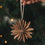 Braune Papierschneeflocke als Christbaumschmuck wird an den Weihnachtsbaum gehängt