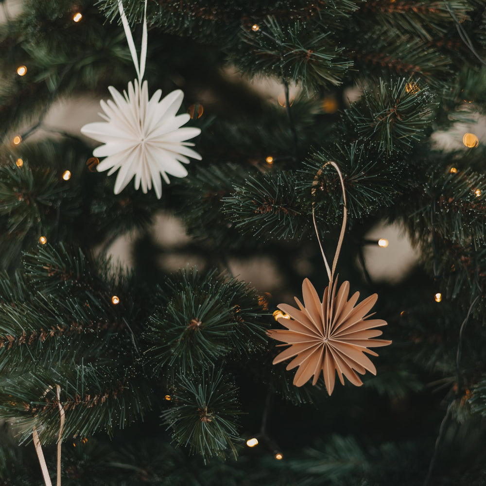 Braune Papierschneeflocken als Weihnachtsanhänger am festlich geschmückten Christbaum