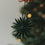 Grüne Papierschneeflocke als Christbaumschmuck wird an den Weihnachtsbaum gehängt