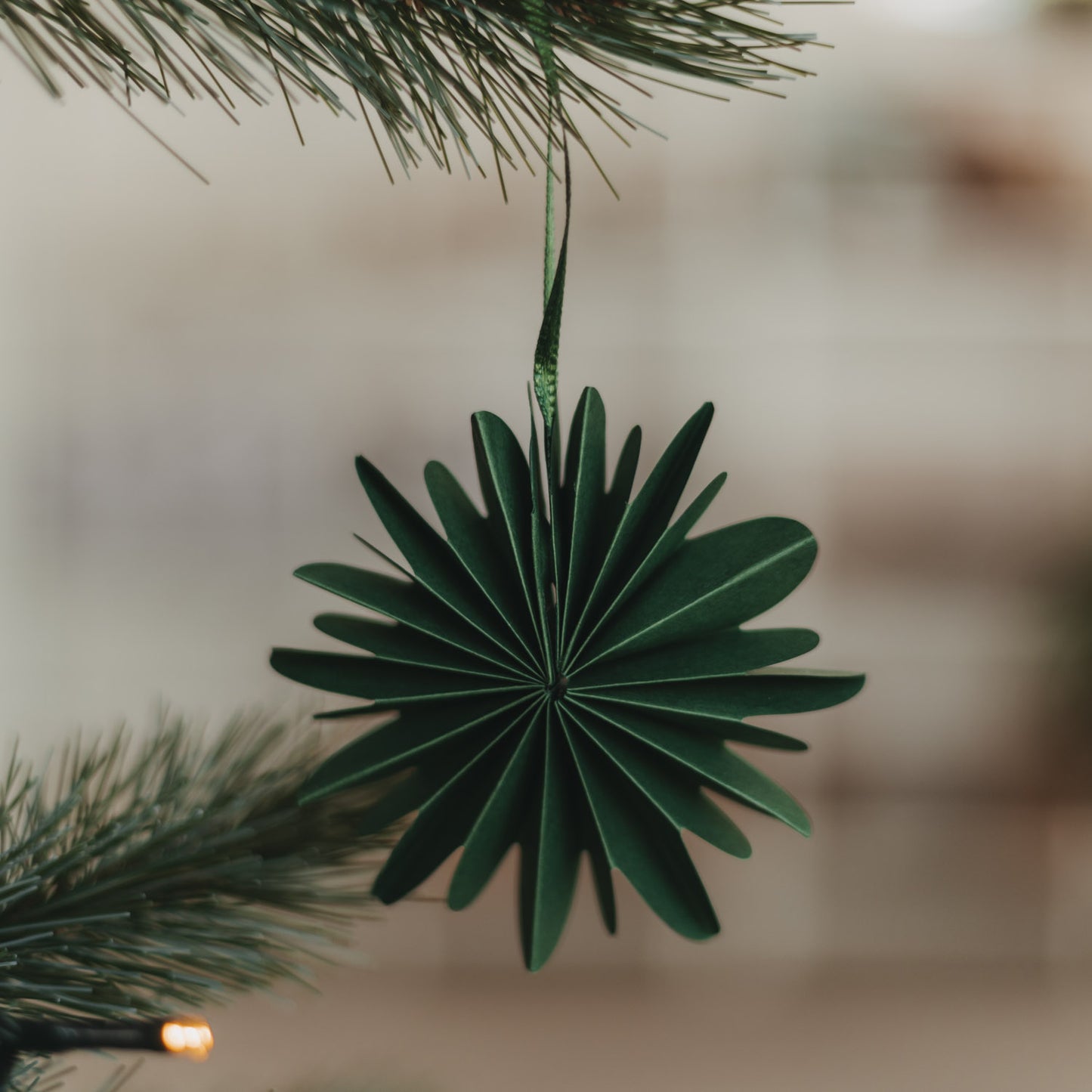 Grüne Papierschneeflocke aus Papier als Weihnachtsbaumschmuck am Tannenzweig
