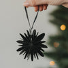 Schwarze Papierschneeflocke als Christbaumschmuck wird am Weihnachtsbaum aufgehängt