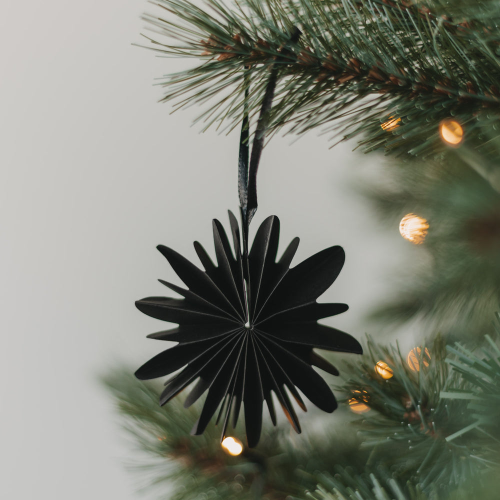 Schwarze Papierschneeflocke als Weihnachtsanhänger am festlich geschmückten Christbaum