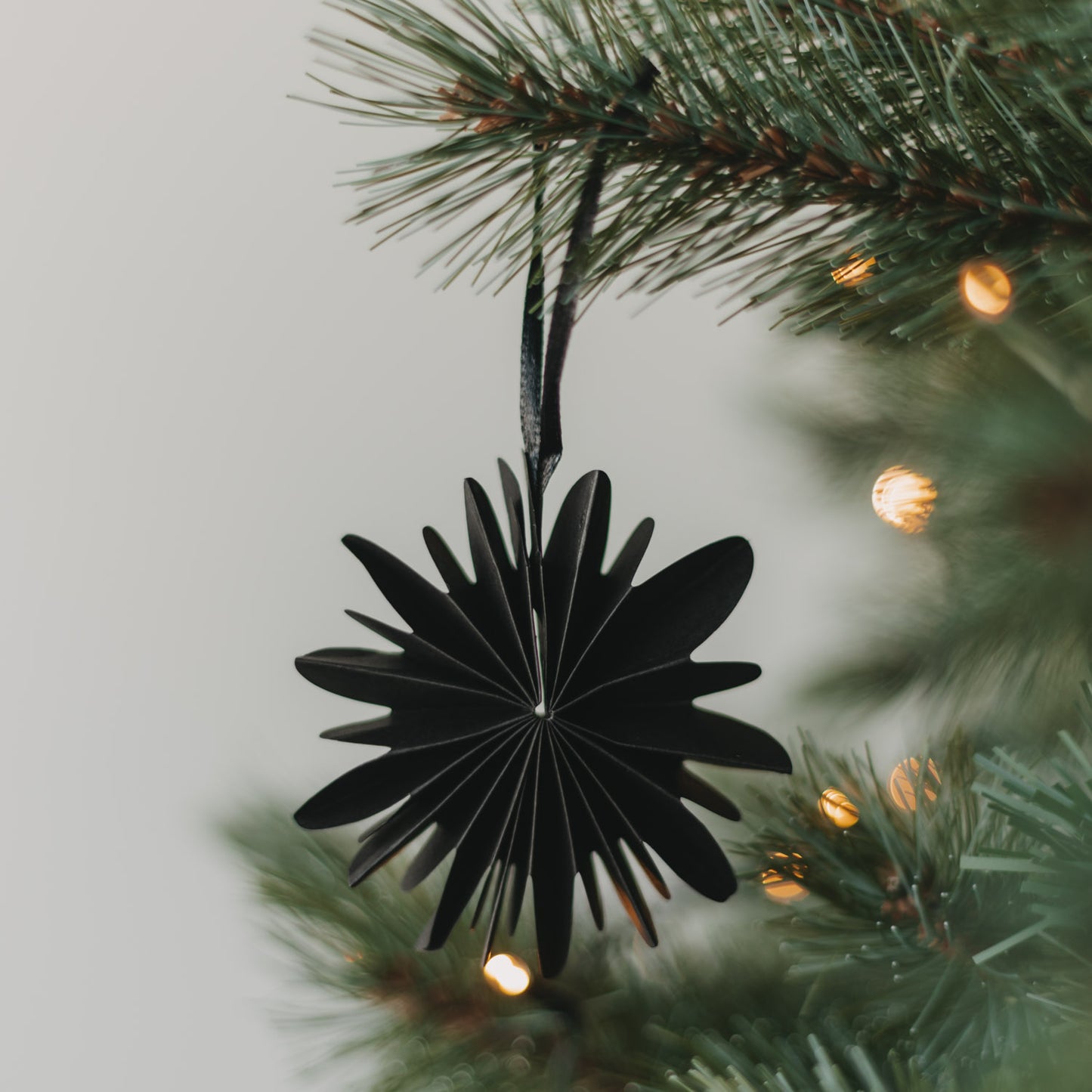 Schwarze Papierschneeflocke als Weihnachtsanhänger am festlich geschmückten Christbaum