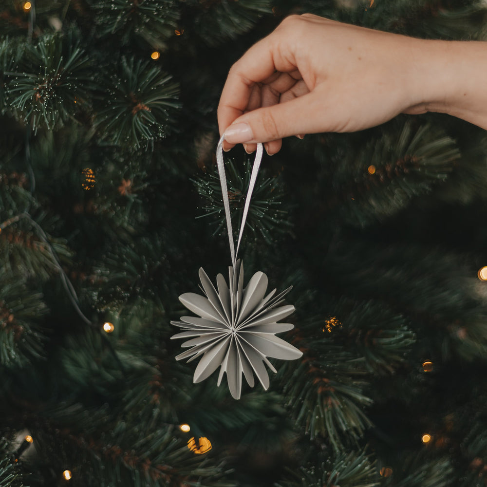 Graue Papierschneeflocke als Weihnachtsanhänger für den Christbaum