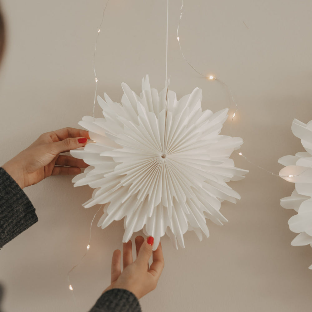 Weiße Papierschneeflocke 30 cm wird an der Wand als Weihnachtsdekoration aufgehängt