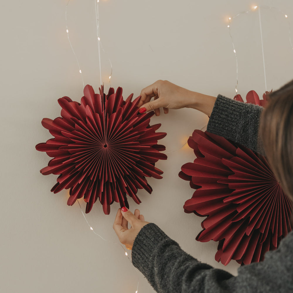Rote Papierschneeflocke 30 cm wird als stilvolle Wanddekoration aufgehängt