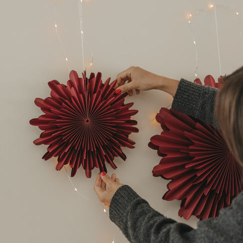 Rote Papierschneeflocke 30 cm wird als stilvolle Wanddekoration aufgehängt