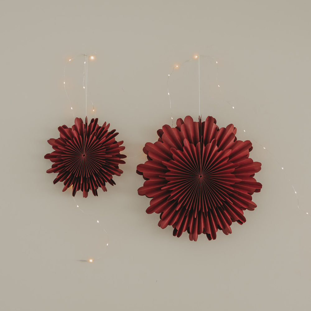Rote Papierschneeflocken in 30 cm und 45 cm als festliche Wanddekoration mit Lichterkette