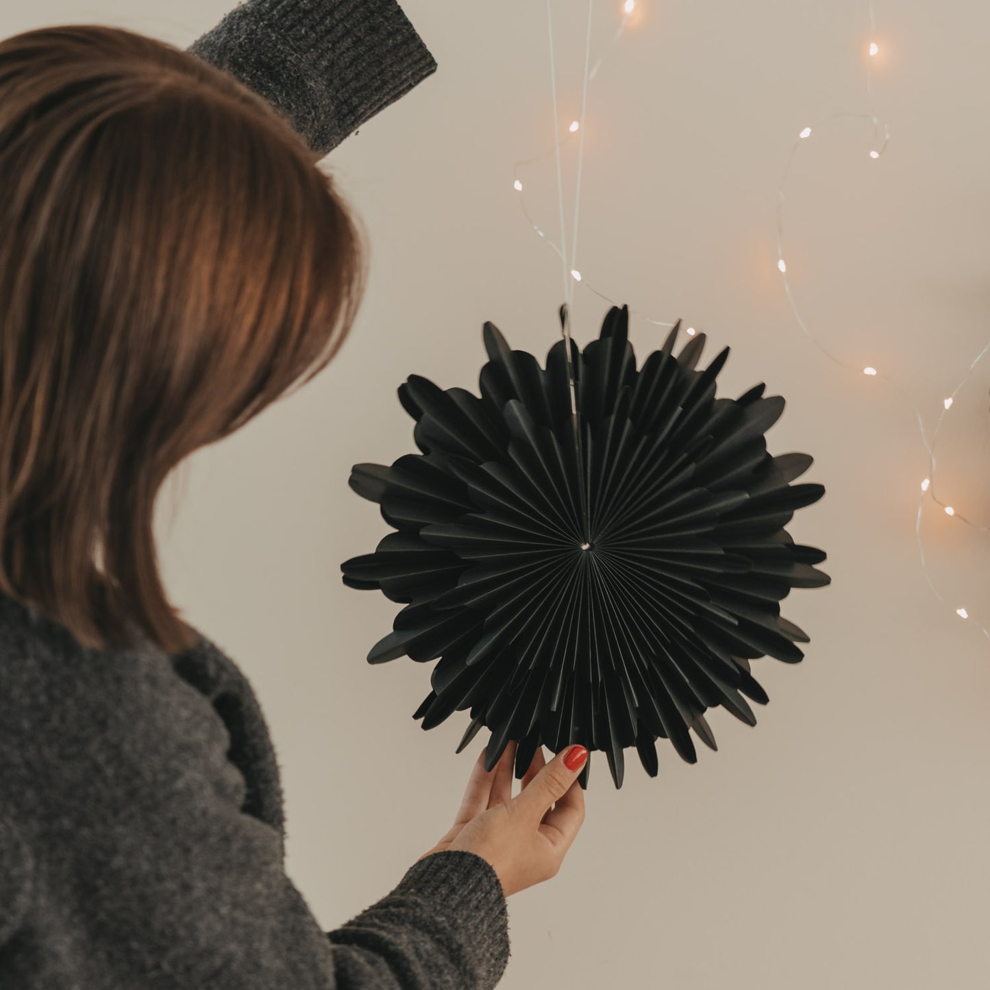 Schwarze Papierschneeflocke 30 cm wird als festliche Wanddekoration aufgehängt