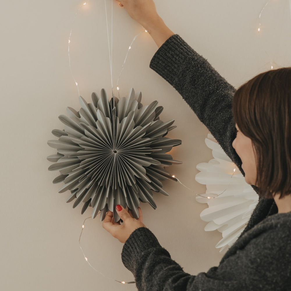 Graue Papierschneeflocke 30 cm wird als Weihnachtsdekoration an der Wand aufgehängt