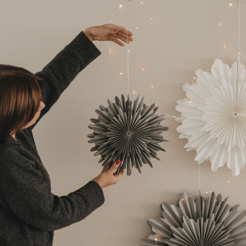 Graue und weiße Papierschneeflocken als festliche Weihnachtsdekoration an der Wand