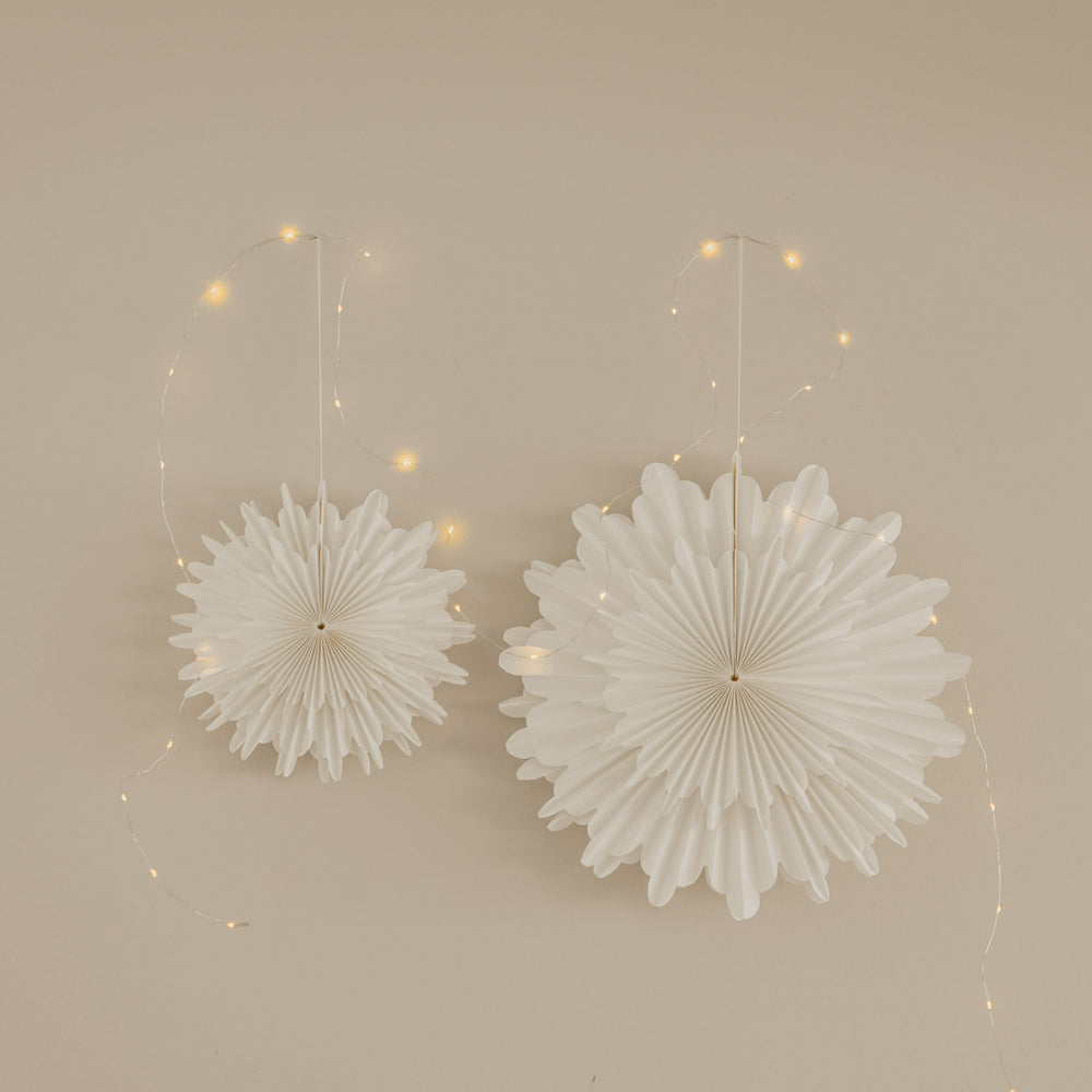 Weiße Papierschneeflocken in 30 cm und 45 cm als festliche Wanddekoration mit Lichterkette