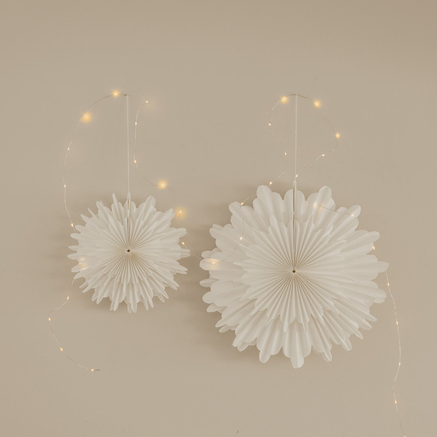 Weiße Papierschneeflocken in 30 cm und 45 cm als festliche Wanddekoration mit Lichterkette