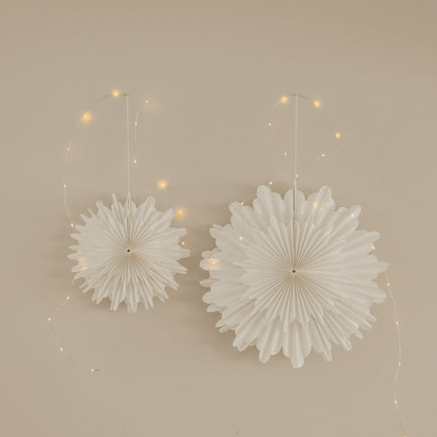 Weiße Papierschneeflocken in 30 cm und 45 cm als festliche Wanddekoration mit Lichterkette