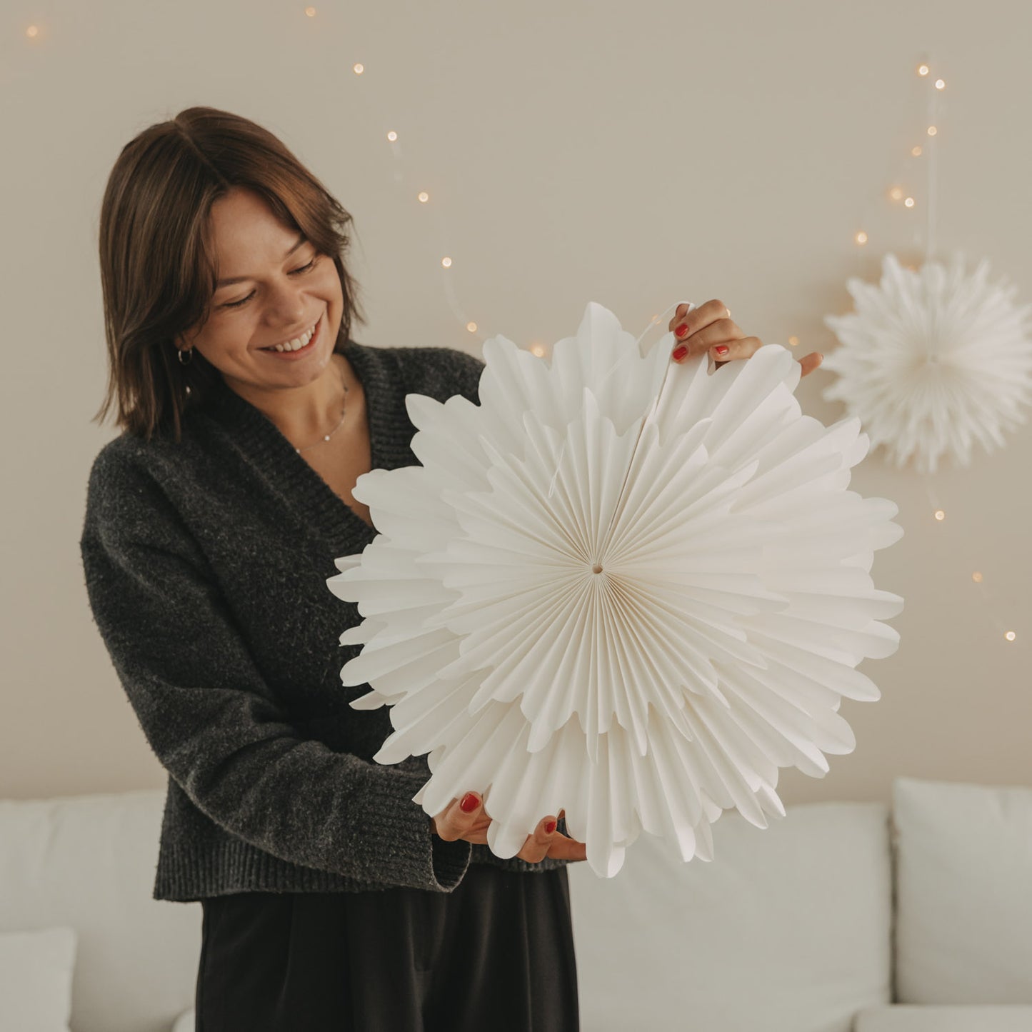 Weiße Papierschneeflocke 45 cm mit filigraner Fächerstruktur in den Händen gehalten