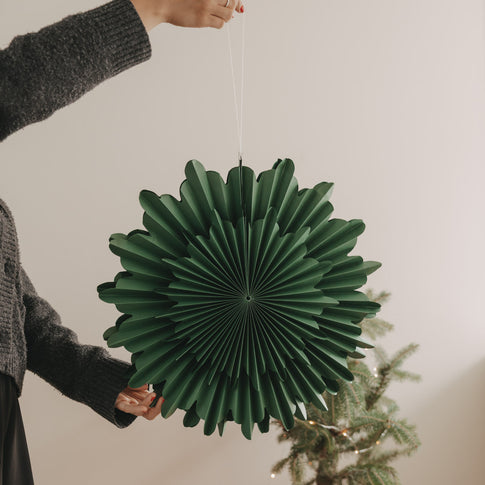 Grüne Papierschneeflocke 45 cm als hängende Weihnachtsdekoration neben Tannenbaum