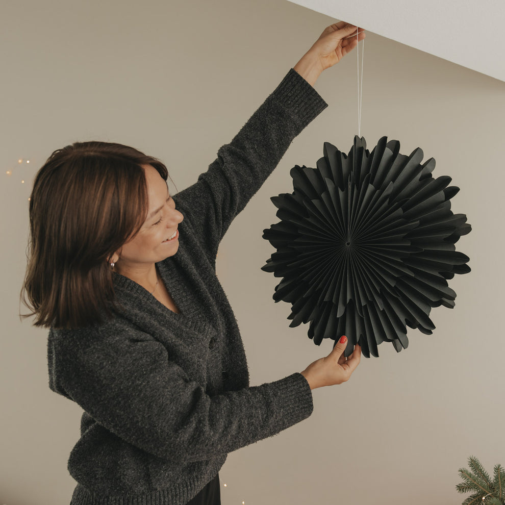 Schwarze Papierschneeflocke 45 cm wird an einer Schnur zur Weihnachtsdekoration befestigt