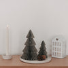 Zwei graue Papiertannen in Wabenoptik mit Kerze und Laterne als minimalistische Weihnachtsdekoration