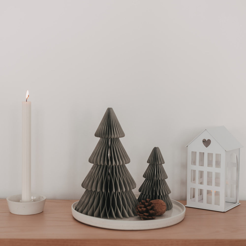 Zwei graue Papiertannen in Wabenoptik mit Kerze und Laterne als minimalistische Weihnachtsdekoration
