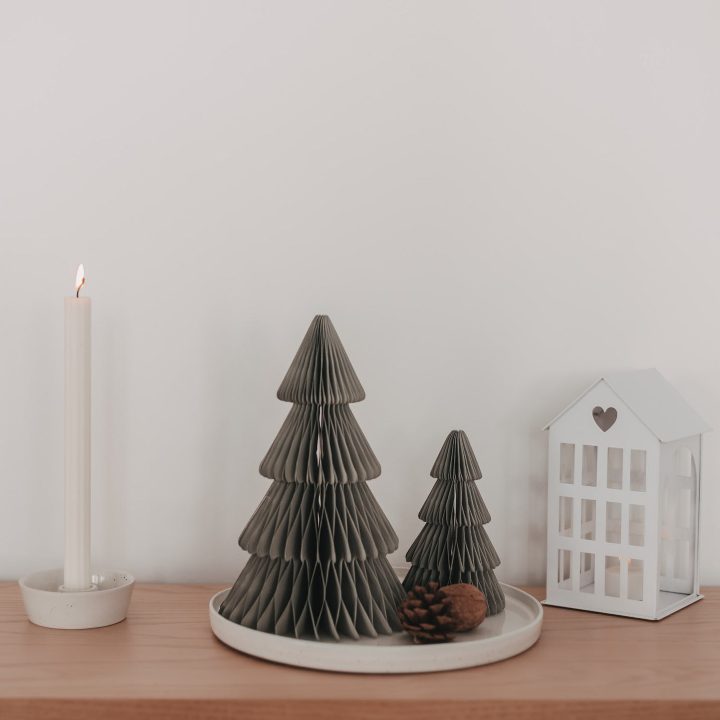 Zwei graue Papiertannen in Wabenoptik mit Kerze und Laterne als minimalistische Weihnachtsdekoration