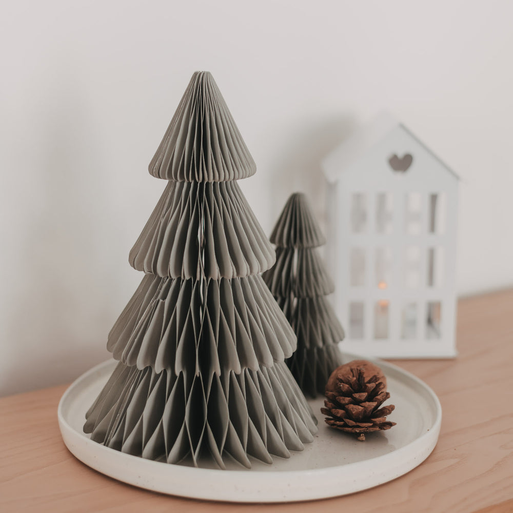 Graue Papiertannen in zwei Größen auf weißem Tablett mit Tannenzapfen als moderne Weihnachtsdeko