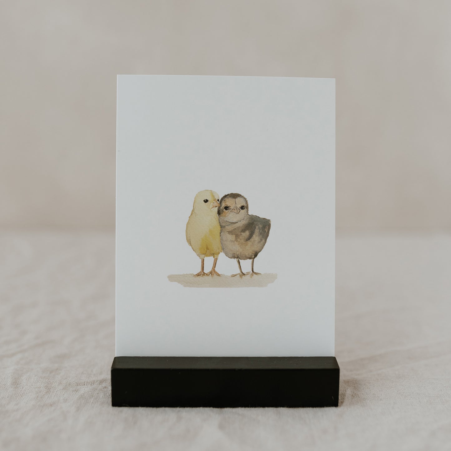 Aquarell-Osterkarte mit zwei süßen Küken im schwarzen Kartenhalter.
