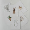 Oster-Kartenset mit sechs Aquarellmotiven locker ausgelegt: Hase, Lamm, Küken, Tulpen und Weidenzweige.