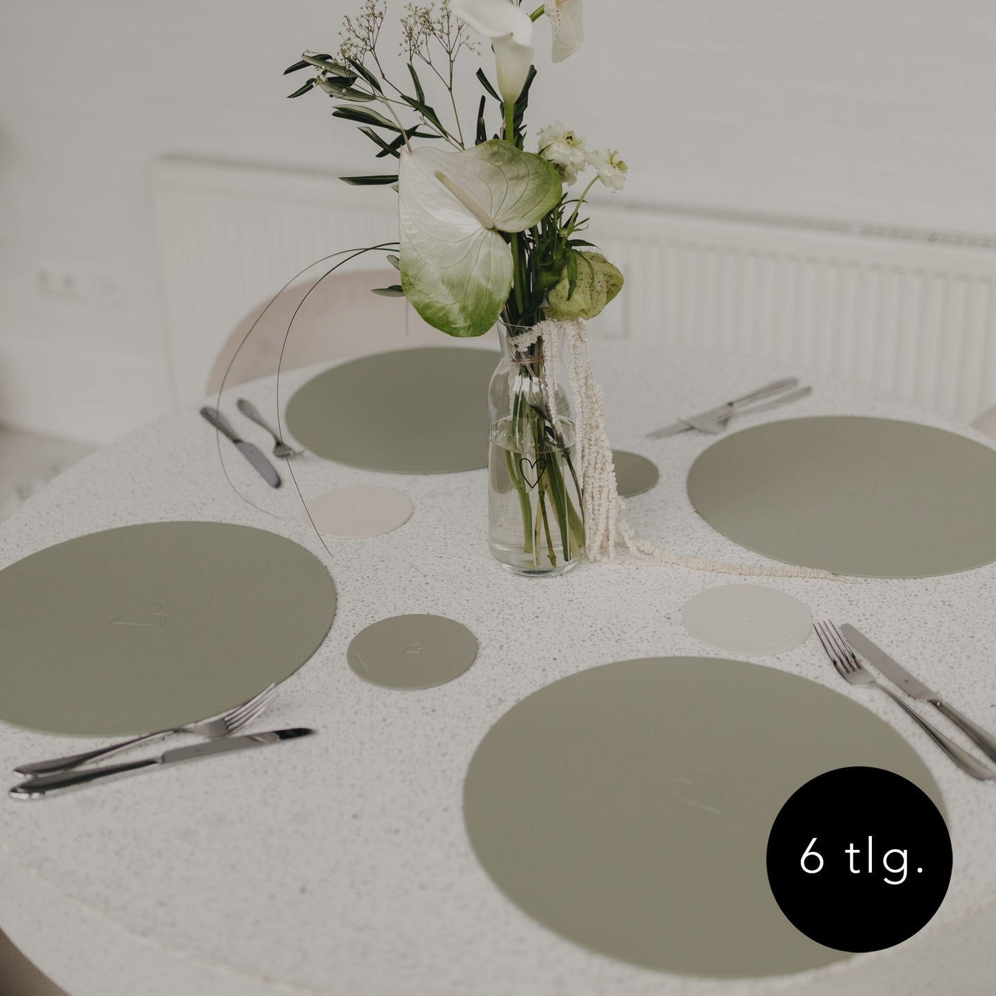 Gedeckter Tisch mit grünen Platzsets und passenden Untersetzern in Grün.