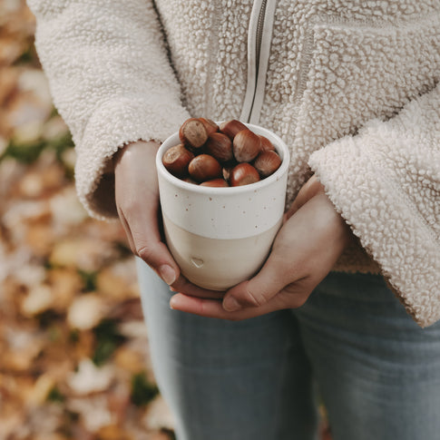 Becher Herz gefüllt mit Haselnüssen – Herbstmoment mit natürlichem Flair.