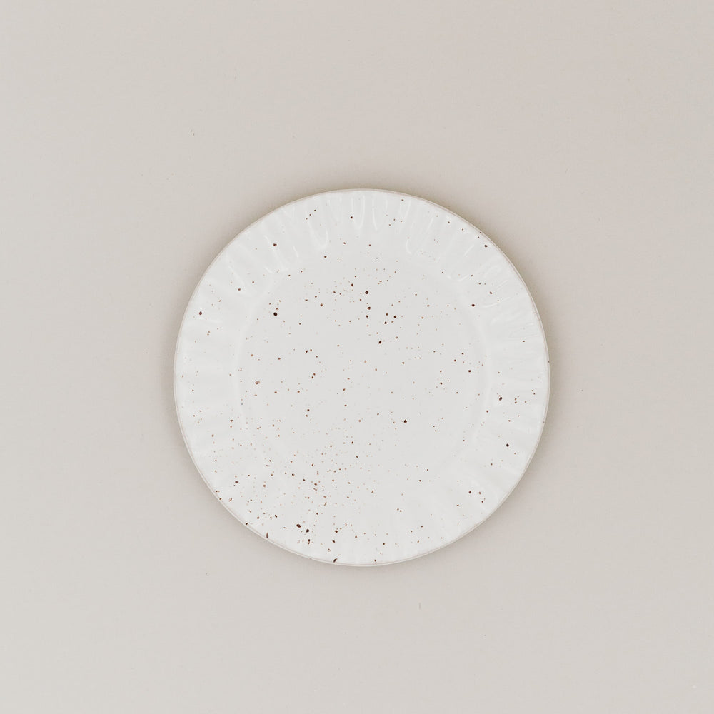 Frühstücksteller Colina von oben mit gesprenkelter Glasur und welligem Rand auf hellem Untergrund