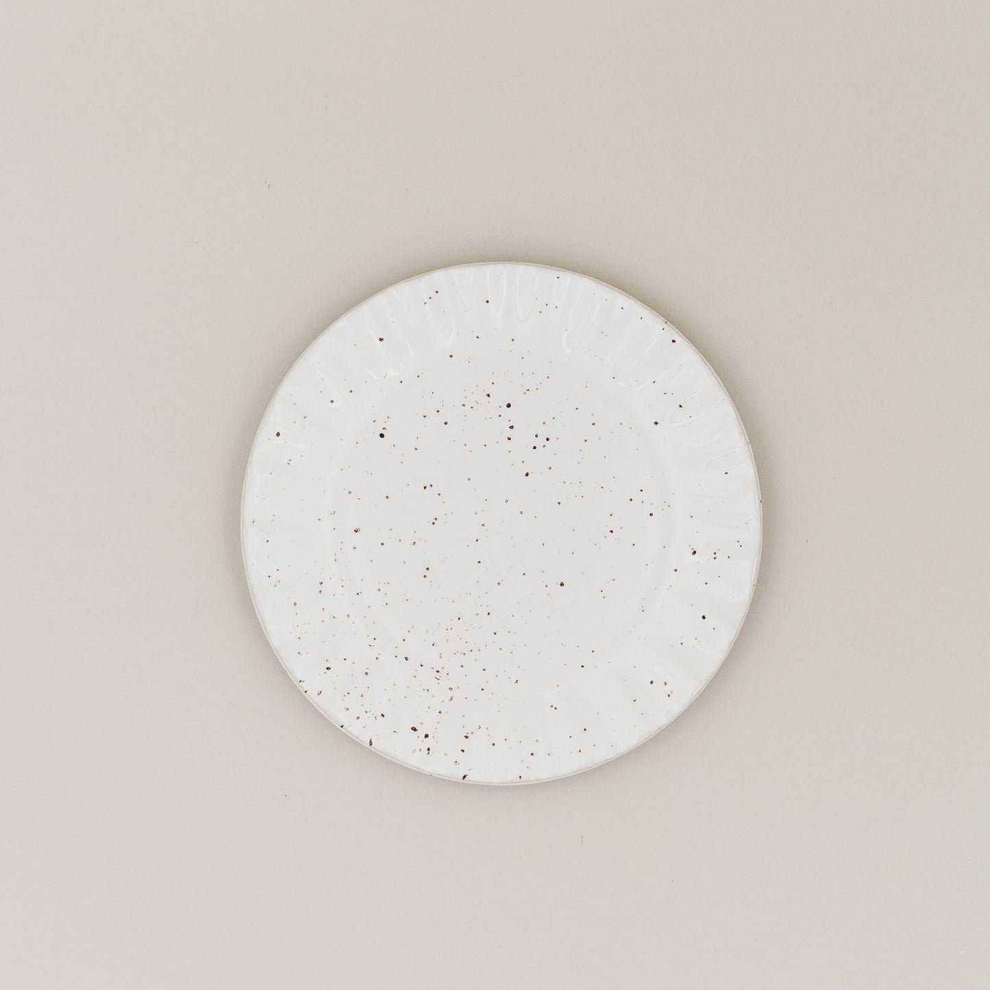 Frühstücksteller Colina von oben mit gesprenkelter Glasur und welligem Rand auf hellem Untergrund