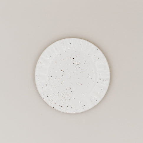 Frühstücksteller Colina von oben mit gesprenkelter Glasur und welligem Rand auf hellem Untergrund