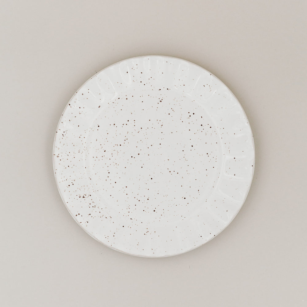 Speiseteller Colina von oben mit gesprenkelter Glasur und welligem Rand auf hellem Untergrund
